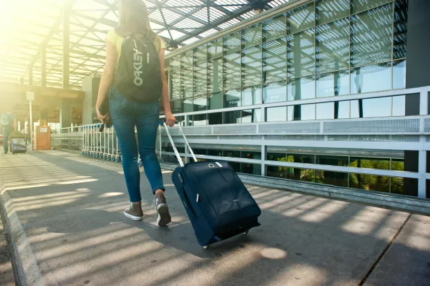 lány bőröndöt húz a repülőtéren - illusztráció