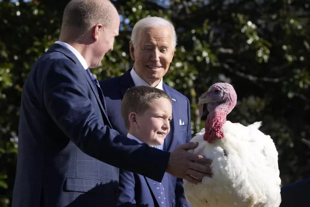Joe Biden a szerencsés pulykával, mellette John Zimmerman, a Pulykatenyésztők Nemzeti Szövetségének elnöke, és annak fia, Grant