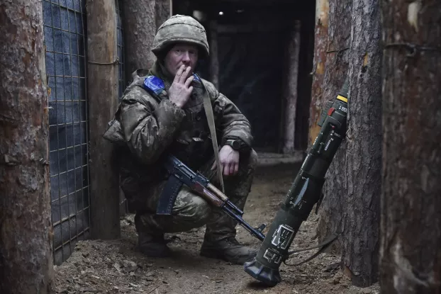 Az ukrán 65. Gépesített Dandár katonája dohányzik a lövészárokban újév napján