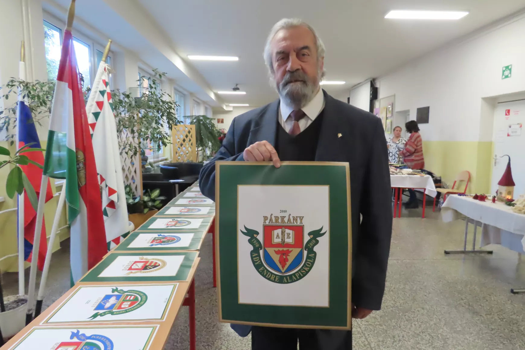 Pécsi L. Dániel az Ady Endre Alapiskola általa tervezett címerével